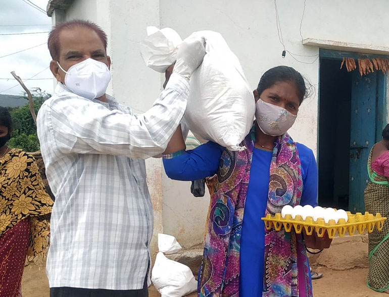 A volunteer and a woman carrying food supplies